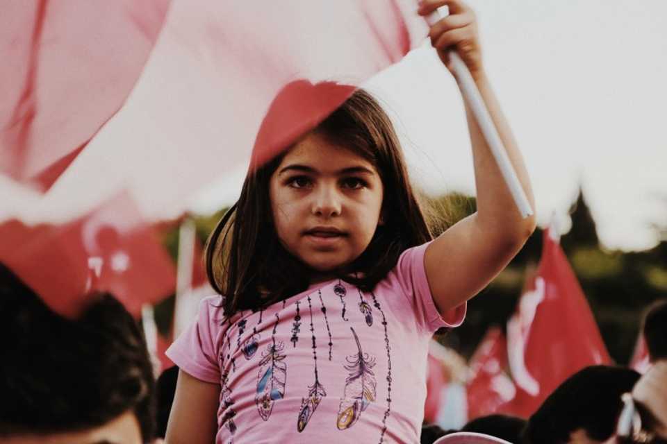 A girl holds the Turkish flag at the event to mark the first anniversary of the defeated coup at the July 15 Martyrs Bridge in Istanbul, Turkey.