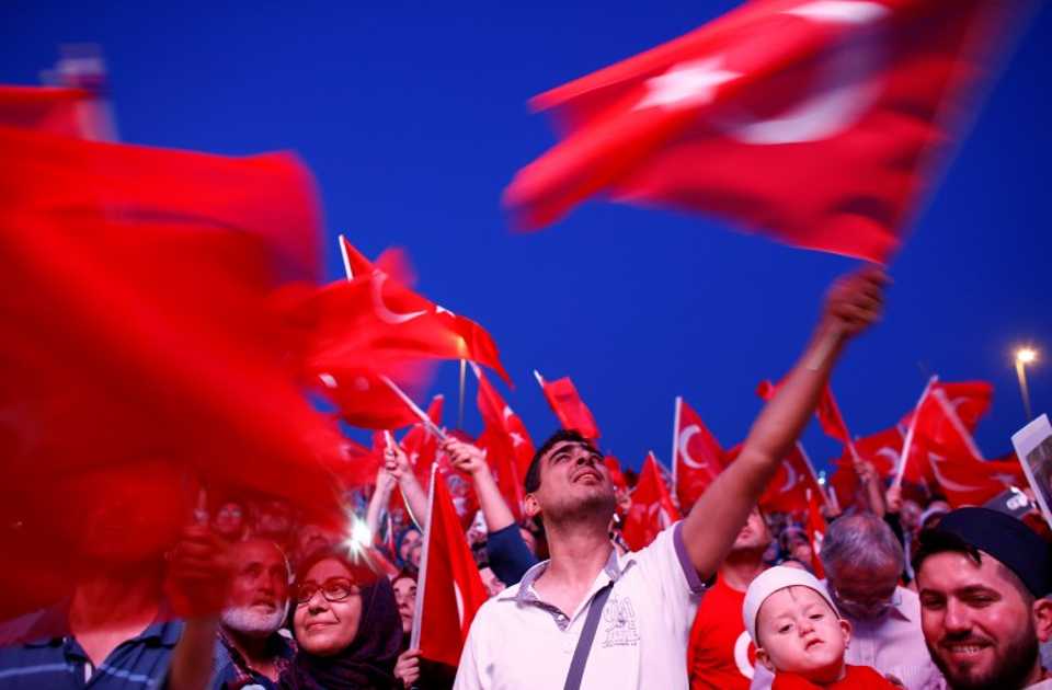 People wave Turkey's national flags as they attend a ceremony marking the first anniversary of the attempted coup at the Bosphorus Bridge in Istanbul, Turkey July 15, 2017. 