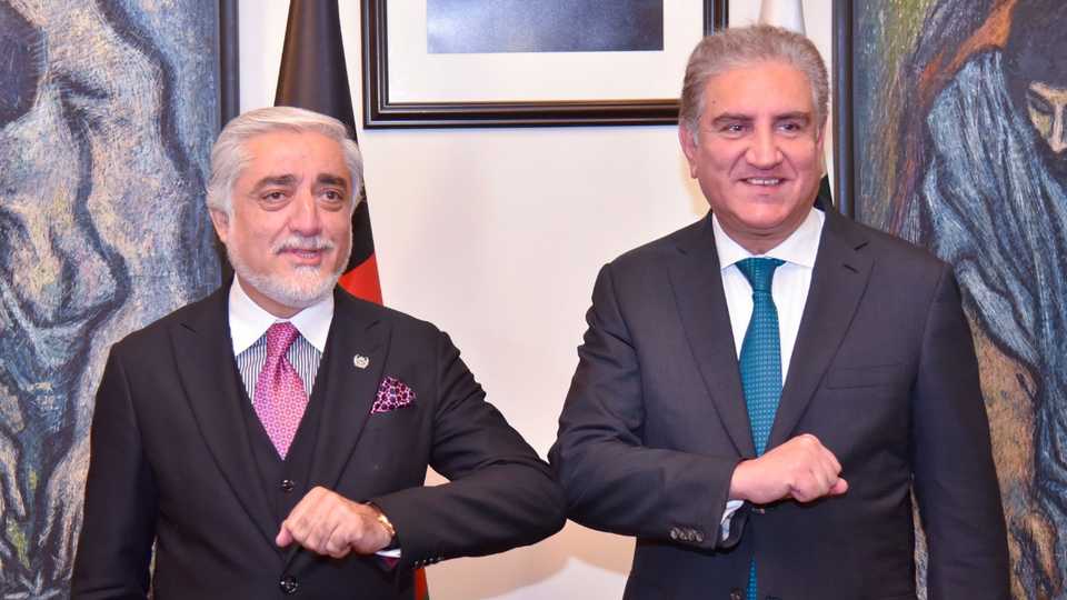 Pakistan's Foreign Minister Shah Mahmood Qureshi (R) bumps elbows with Abdullah Abdullah, the head of Afghanistan's peace council, upon his arrival in Pakistan on September 28, 2020.