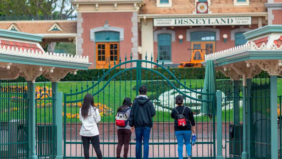 People stand outside the gates of Disneyland Park on the first day of the closure of Disneyland and Disney California Adventure theme parks in Anaheim, March 14, 2020.
