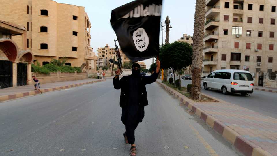 A Daesh member waves the group's flag in Raqqa, Syria, on June 29, 2014.