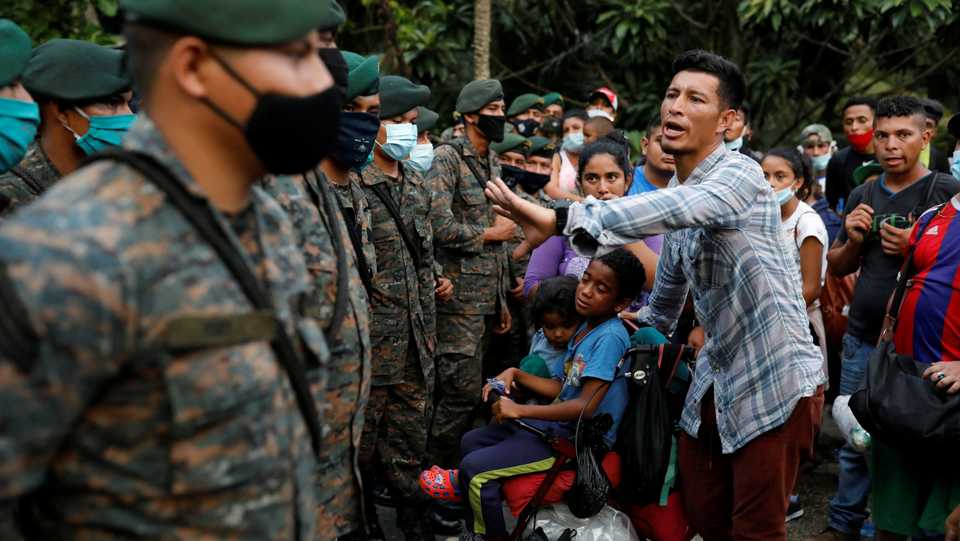 A Honduran migrant trying to reach the US with his sons talks to Guatemalan soldiers blocking a road to stop migrants from reach the Mexico's border, in Izabal, Guatemala on October 2, 2020.