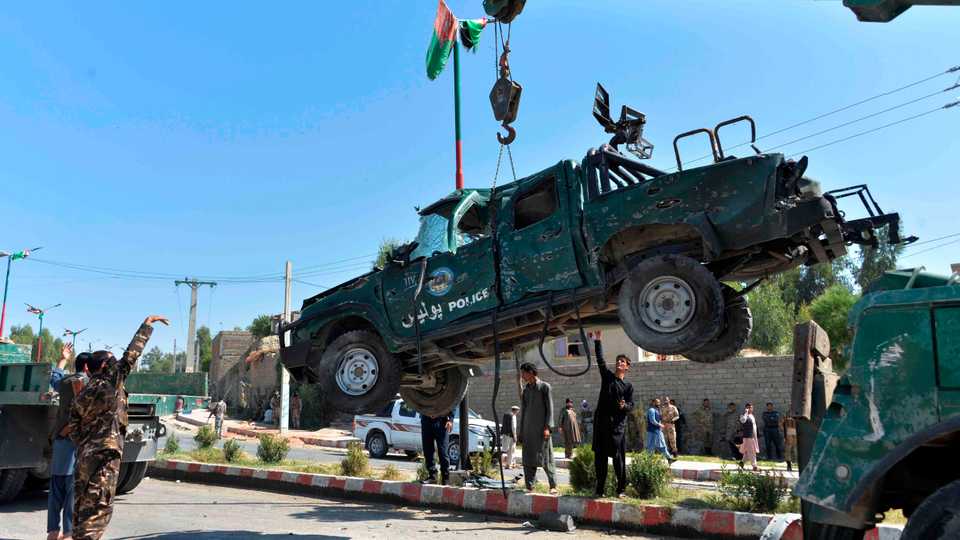 Afghan security forces removes a damaged police vehicle at the site of a car bomb attack that targeted Laghman provincial governor's convoy, in Mihtarlam, Laghman Province on October 5, 2020.