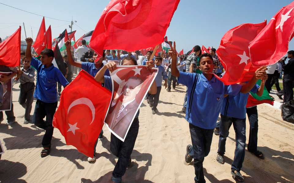 Palestinian youths hold up Turkish flags and a picture of Turkish Prime Minister Recep Tayyip Erdogan as they march in the port of Gaza City, Sept. 13, 2011.