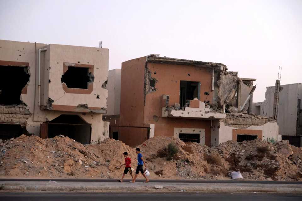 Boys walk past destroyed houses during past fighting with Daesh militants in Sirte, Libya August 17, 2020.