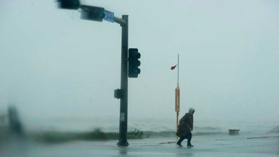 A man walks across a street as the outer bands of Hurricane Delta make landfall in Galveston, Texas. on October 9, 2020.