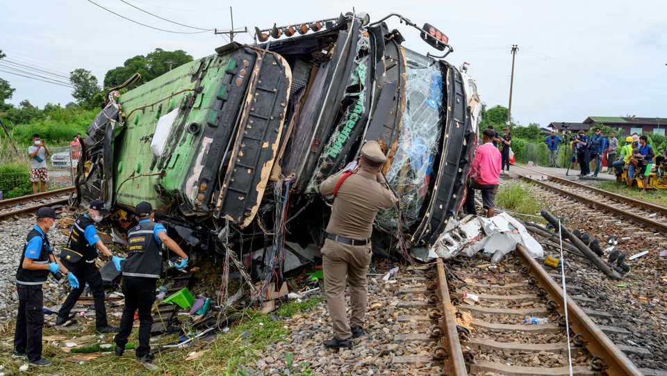 Investigators work by the wreckage of an overturned bus involved in a deadly collision with a train next to Khlong Kwaeng Klan railway station in Chachoengsao province, Thailand, October 11, 2020.