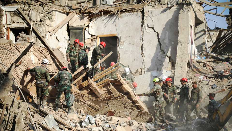 Rescuers work at the scene of a damaged building after Armenia attacked Ganja city in Azerbaijan on Sunday, October 11, 2020.