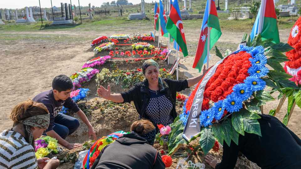 Family members and Aybeniz Khasanova (C), the mother of 29-years-old soldier killed during clashes with Armenia, next to his grave near Agdam city during the military conflict over the breakaway region of Nagorno-Karabakh on October 15, 2020.