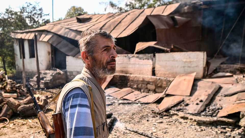 An armed villager inspects the grounds of a neighbour's home destroyed by shelling following an overnight attack during the ongoing fighting between Armenia and Azerbaijan over occupied Karabakh, in the Martakert region on October 15, 2020.
