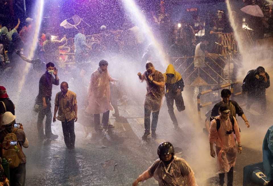 Pro democracy demonstrators face water canons as police try to disperse them from their protest venue in Bangkok, Thailand, Friday, Oct. 16, 2020.