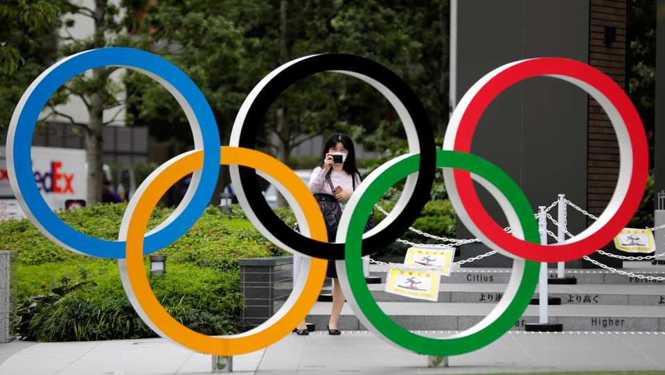 A woman takes a picture of the Olympic rings in front of the National Stadium in Tokyo, Japan. October 14, 2020.