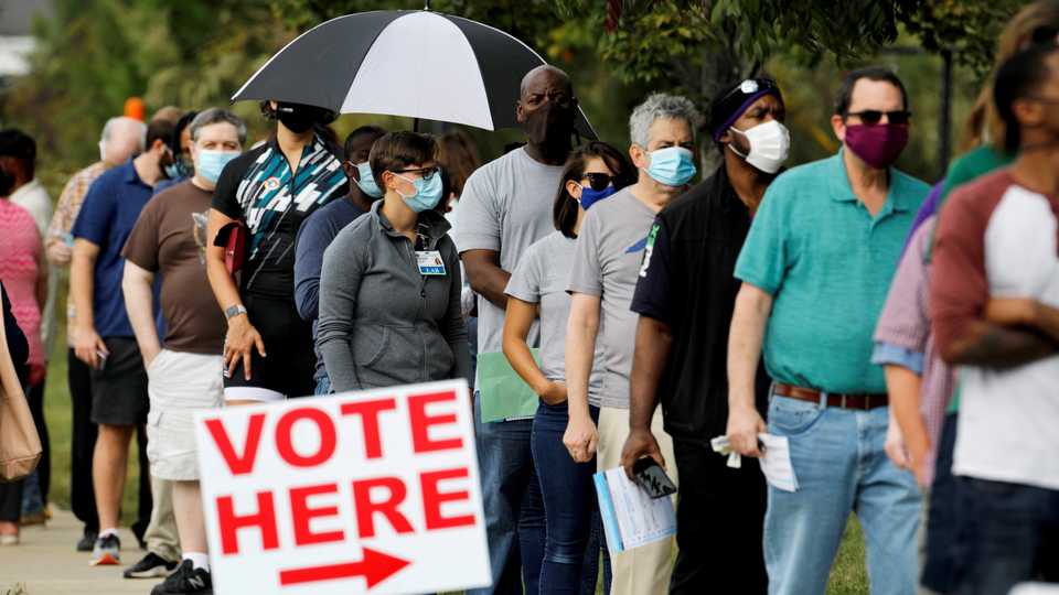 Voters wait in line to enter a polling place and cast their ballots on the first day of the state's in-person early voting for the general elections in Durham, North Carolina, US on October 15, 2020.