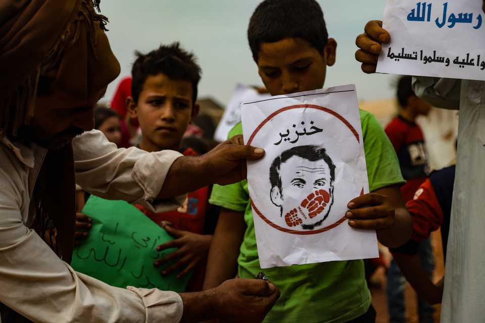 Citizens, holding banners, gather to stage a demonstration to protest against French President Emmanuel Macron’s statements of Islam and Muslims, on October 25, 2020 in Idlib, Syria.