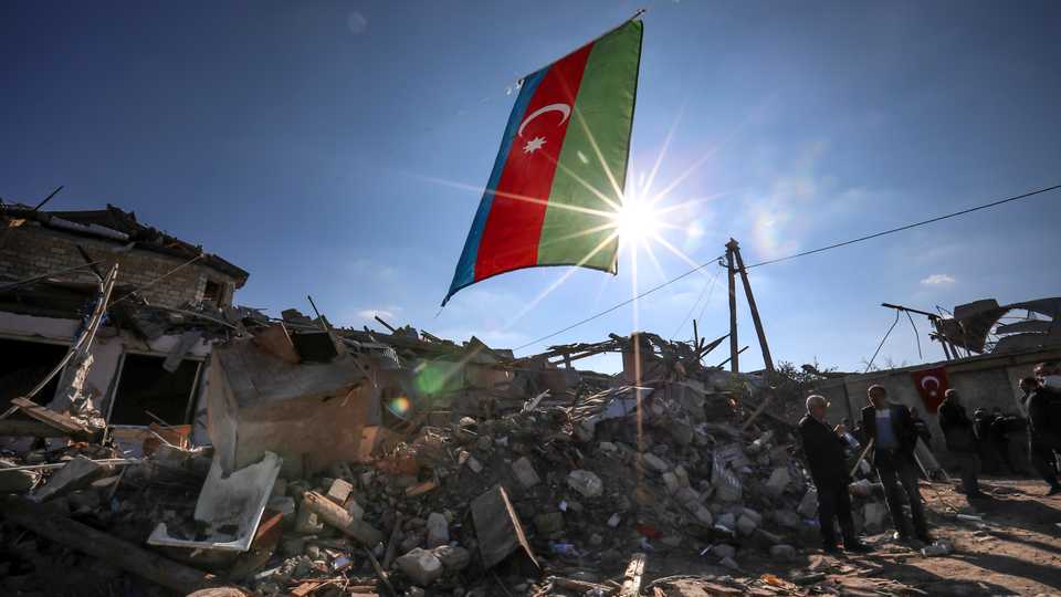 Azerbaijan's national flag flies over destroyed houses in a residential area that was hit by rocket fire overnight by Armenian forces, October 22, 2020 in Ganja, Azerbaijan.