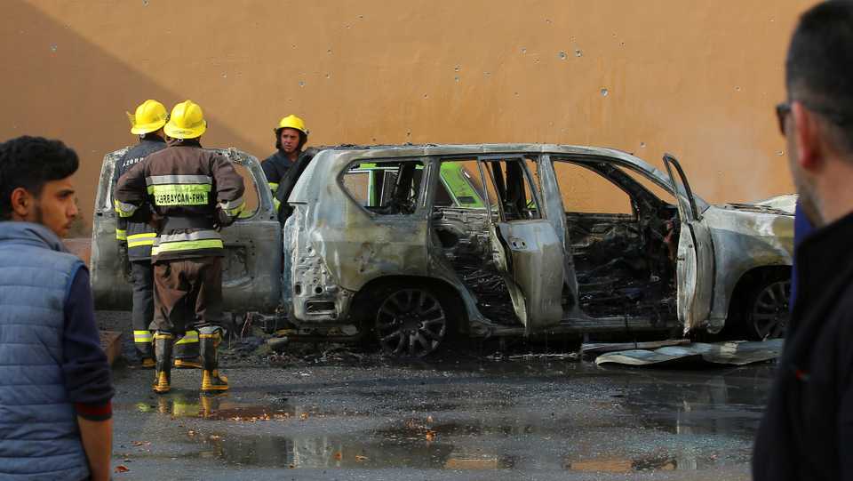 Firefighters gather near a burnt car, which was hit by shelling in the town of Barda, Azerbaijan on October 28, 2020.