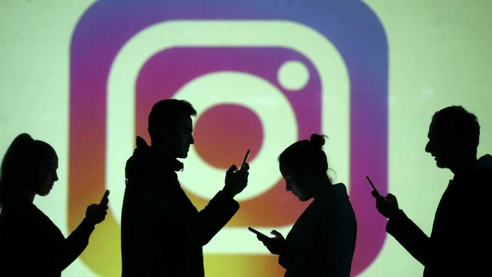 Silhouettes of mobile users are in front of a screen projection of the Instagram logo in this picture illustration taken on March 28, 2018.