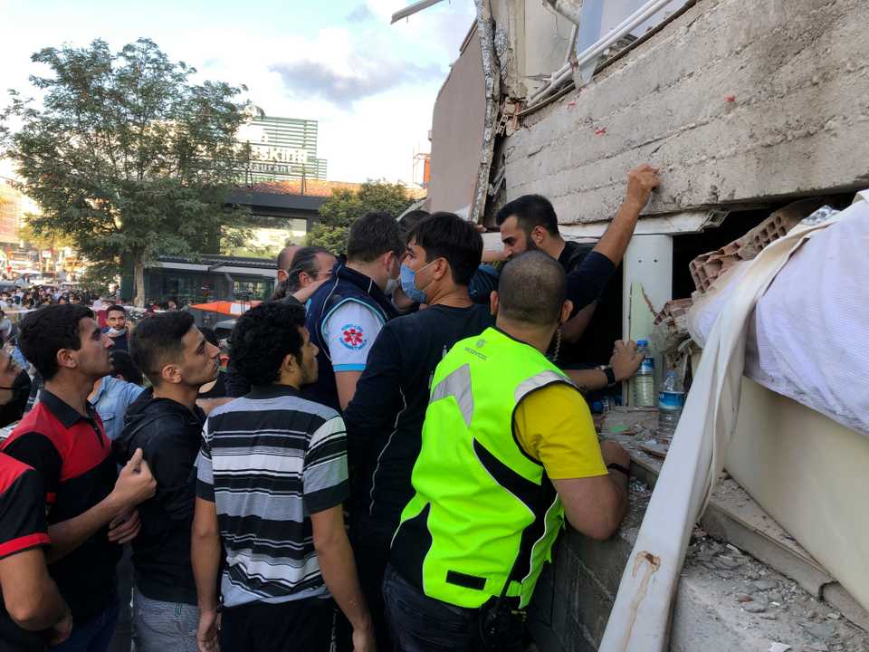 Rescue workers and local people try to reach residents trapped in the debris of a collapsed building, in Izmir, Turkey, October 30, 2020.