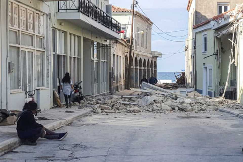 People walk past a destroyed house after an earthquake in the island of Samos on October 30, 2020.