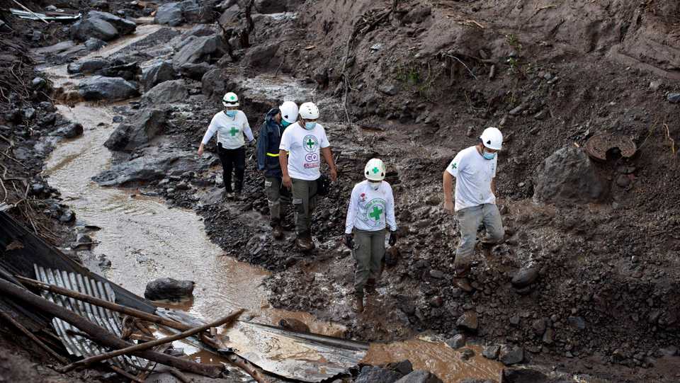 A team of rescuers of the Green Cross traverse a watercourse left after a landslide in search of victims in Nejapa, El Salvador on October 30, 2020.
