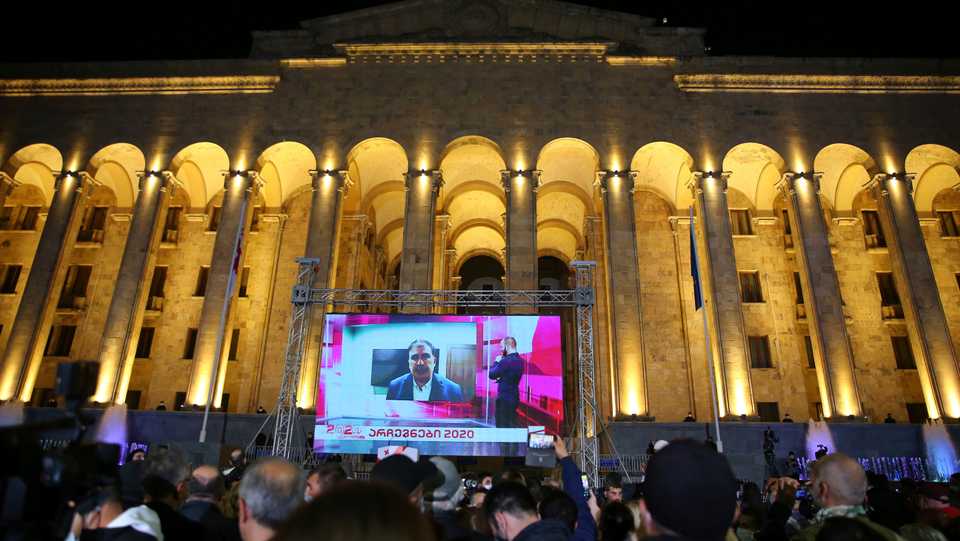 Supporters of Georgian ex-President Mikheil Saakashvili's United National Movement watch his address on a big screen in front of the Parliament's building after the parliamentary elections in Tbilisi, Georgia, Saturday, Oct. 31, 2020.