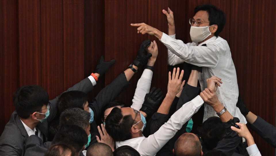 In this file photo taken on May 8, 2020, pro-democracy lawmaker Eddie Chu Hoi-dick (top C) shouts at security trying to restrain him after pro-Beijing lawmaker Starry Lee (not seen) sat in the chairperson’s seat before a key committee meeting at the Legislative Council in Hong Kong.