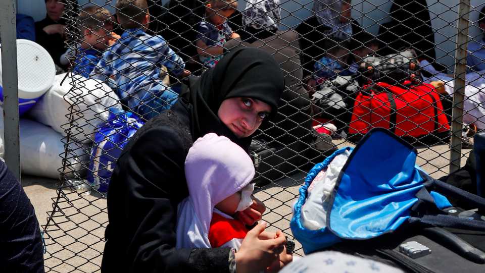 A Syrian woman and child living in Turkey wait to cross into Syria at the Oncupinar border crossing, near the town of Kilis, Turkey, June 13, 2017. 