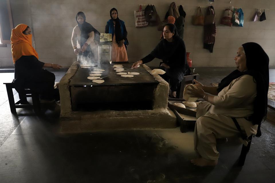 Women volunteers prepare roti (Indian bread). Around 200,000 rotis are prepared every day which is later served to individuals visiting the kitchen.