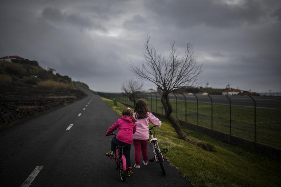 Duas mulheres andam de bicicleta na estrada com o aeroporto do Corvo, na Vila do Corvo, nos Açores, a 10 de março de 2022.