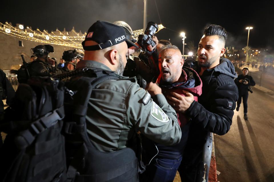 An Israeli police officer confronts a man carrying a camera during clashes near Damascus Gate, just outside Jerusalem's Old City, during the Muslim holy fasting month of Ramadan, in Jerusalem, April 22, 2021.