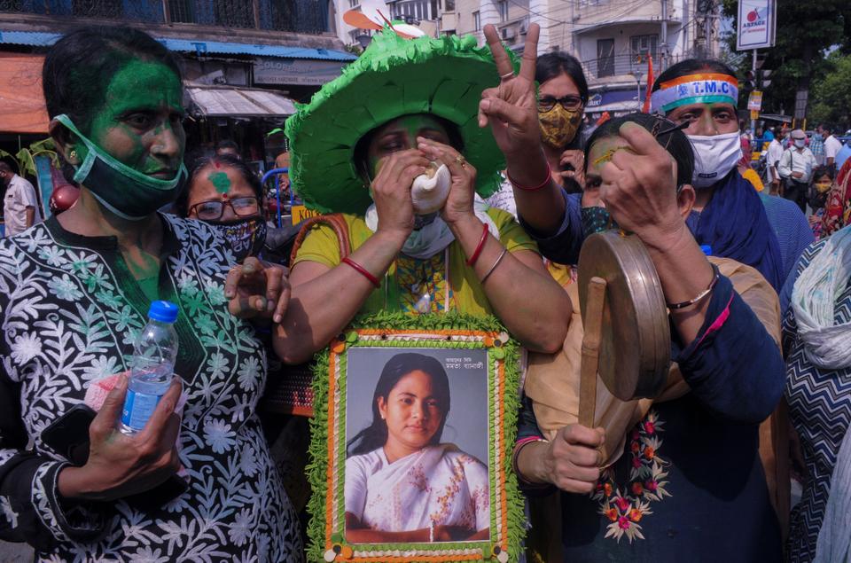 Supporters of Trinamool Congress party chief Mamata Banerjee holding an earlier photograph of her celebrate early lead for the party in the West Bengal state elections in Kolkata, India, Sunday, May 2, 2021.