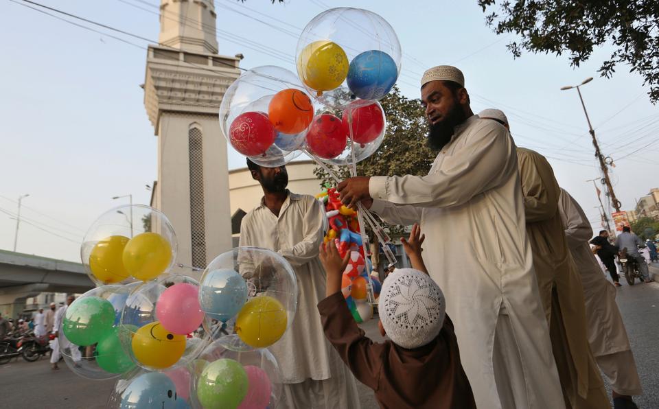 A man purchases balloons for his children after performing an Eid al Fitr prayer at a mosque in Karachi, Pakistan.