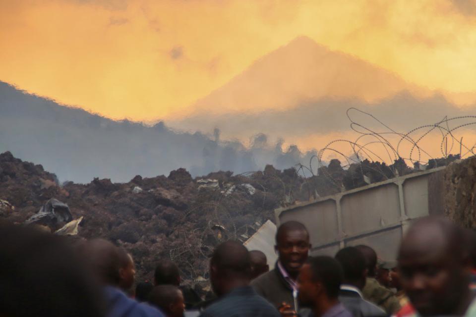 Residents check the damages caused by lava from the overnight eruption of Mount Nyiragongo, seen in background, in Buhene, on the outskirts of Goma, Congo in the early hours of Sunday, May 23, 2021.