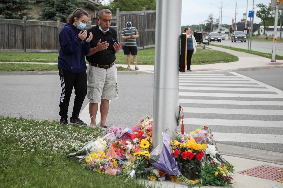 Abdullah Alzureiqi and his daughter Hala say a prayer at the fatal crime scene where a man driving a pickup truck jumped the curb and ran over a Muslim family in London, Ontario, Canada June 7, 2021.