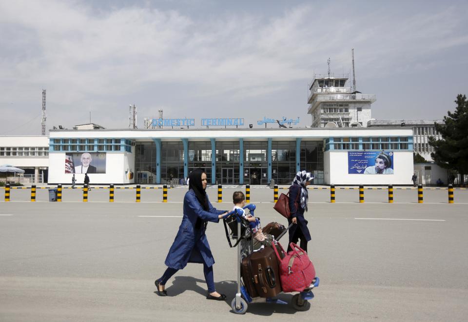 Afghan passengers walk in front of Hamid Karzai International Airport in Kabul, Afghanistan March 29, 2016.