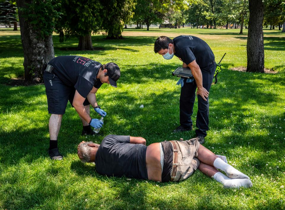 Firefighters check on the welfare of a man in Mission Park in Spokane, Washington on June 29, 2021.