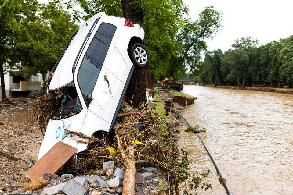 A car washed up by the flood leans against a tree while the river Ahr can be seen in the background, in Bad Neuenahr, Germany, Friday, July 16, 2021.