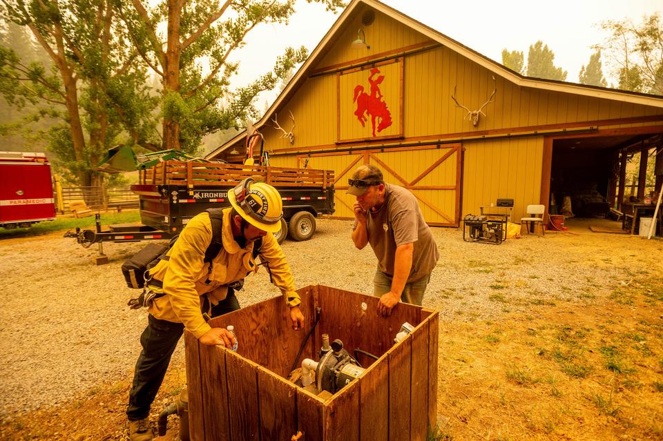 Jesse Ackley and firefighter Sergio Zavala examine a water pump while preparing for the Dixie Fire's approach in Plumas County, California, July 25, 2021.