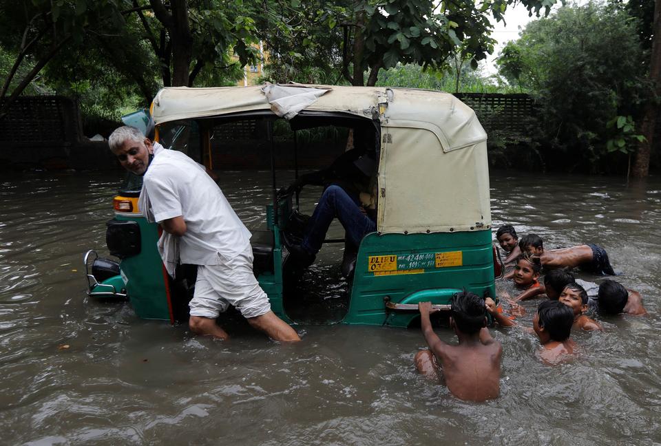 A man pulls his auto rickshaw through waterlogged street after heavy rains in New Delhi, India, July 27, 2021.