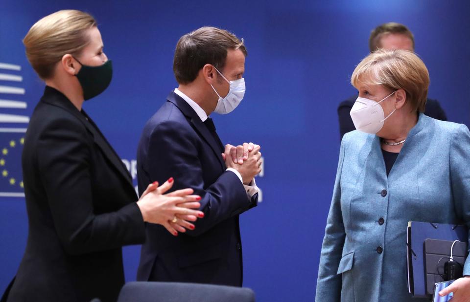 German Chancellor Angela Merkel speaks with French President Emmanuel Macron during a round table meeting at an EU summit in Brussels, Oct. 15, 2020.