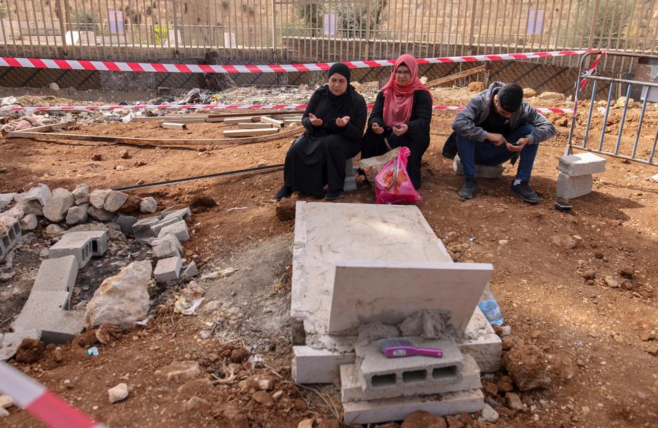 Palestinians visit the tomb of a relative in a sector of the Al-Yousufiya cemetery near the Lion's Gate entrance to the Al-Aqsa mosque where Israelis have demolished several graves, to establish a national park