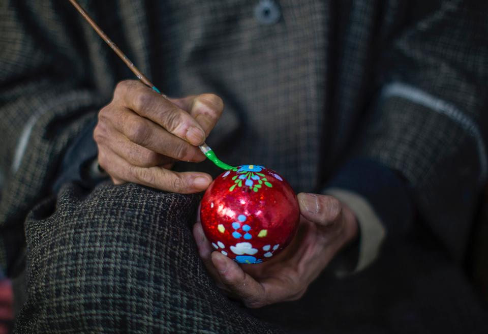 An artisan paints a Christmas bulb.