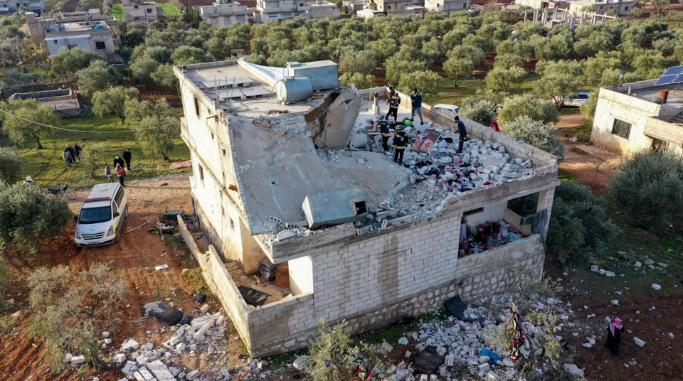 People inspect a destroyed house following an operation by the US military in the Syrian village of Atmeh.