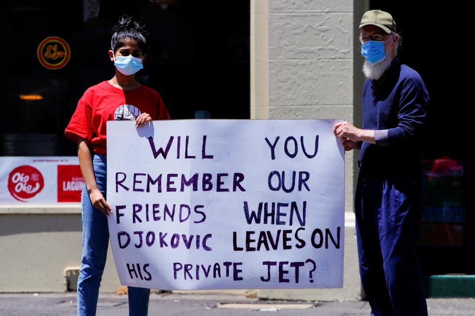 I manifestanti pro-rifugiati tengono un cartello fuori dal Park Hotel, dove il tennista serbo Novak Djokovic si terrà durante il suo soggiorno a Melbourne, in Australia, il 9 gennaio 2022.