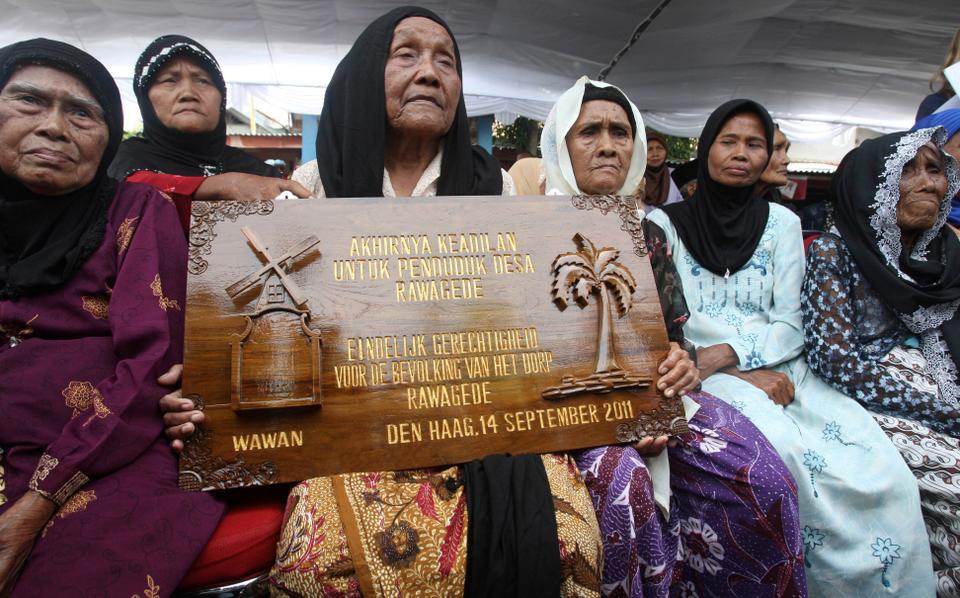 Surviving widows and relatives of Indonesian men killed in a notorious massacre conducted by the Dutch military pose with a plaque which reads 