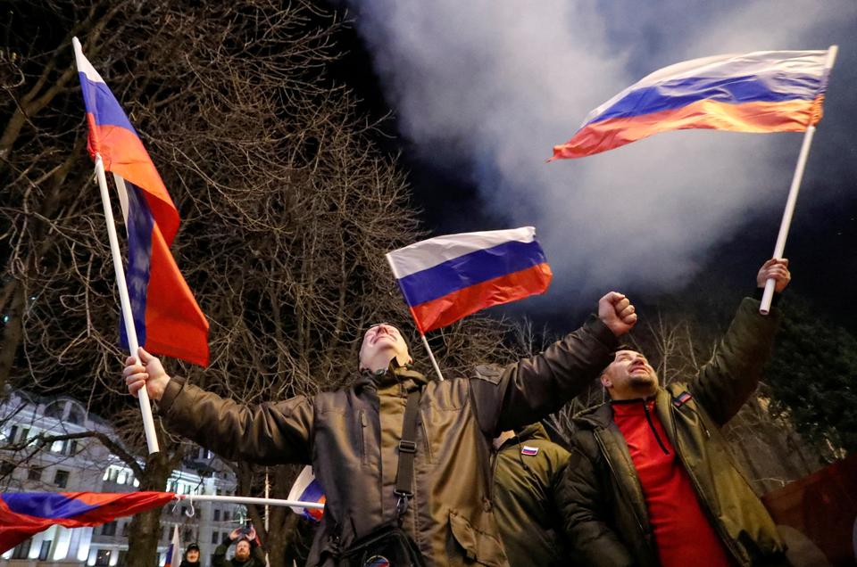 Pro-Russian activists react on a street as fireworks explode in the sky, after Russian President Putin signed a decree recognising two Russian-backed breakaway regions in eastern Ukraine as independent entities, in the separatist-controlled city of Donetsk, February 21, 2022.