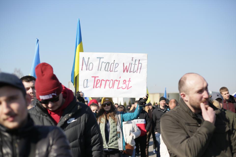 Protesters hold placards at a demonstration against EU trade with Russia on Saturday, March 19.