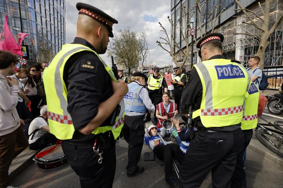 City of London police speak with activists from the climate change protest group Extinction Rebellion (XR) as they block Blackfriars Bridge in London on April 15, 2022, one of a series of actions aiming to stop the fossil fuel economy.