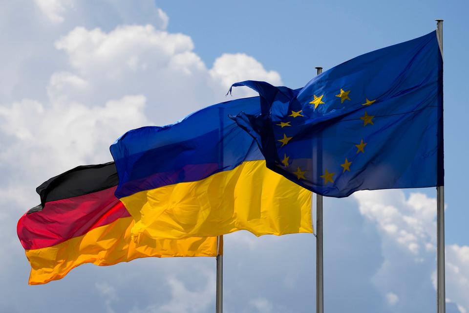 The Ukrainian national flag waves between the Europa flag, right, and the German national flag, right, in front of the Reichstag building during a debate at the German parliament Bundestag in Berlin.