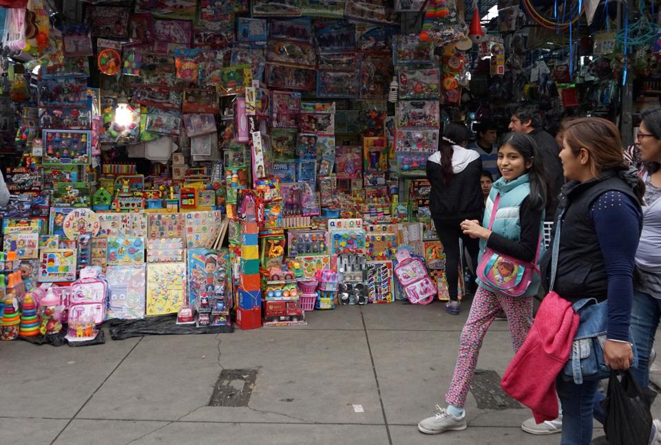 People walk past a stand that sells toys and other products imported from China at Central Market in Lima, Peru.
